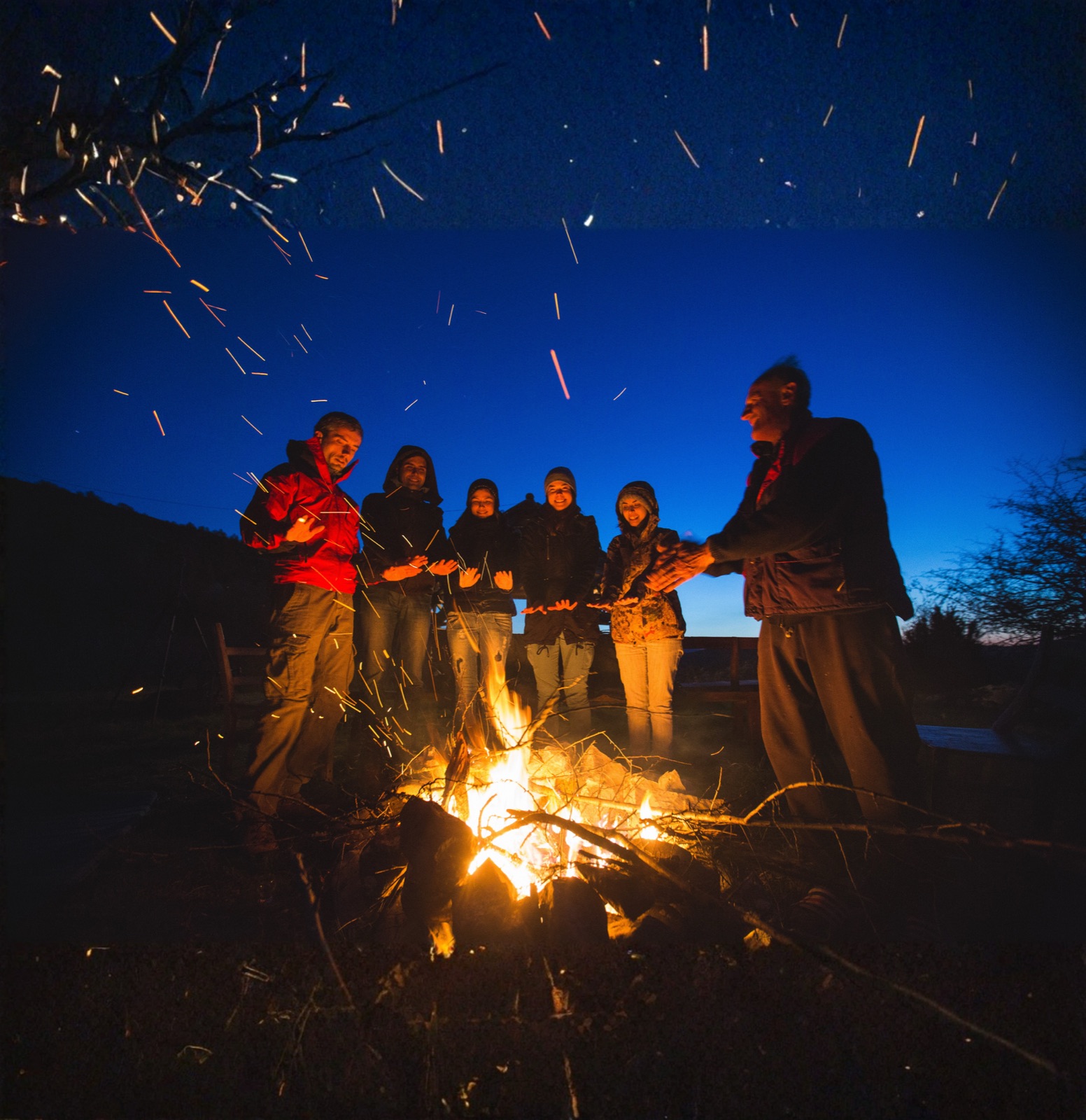 Gece kamp ateşinin etrafında ısınan bir grup insan